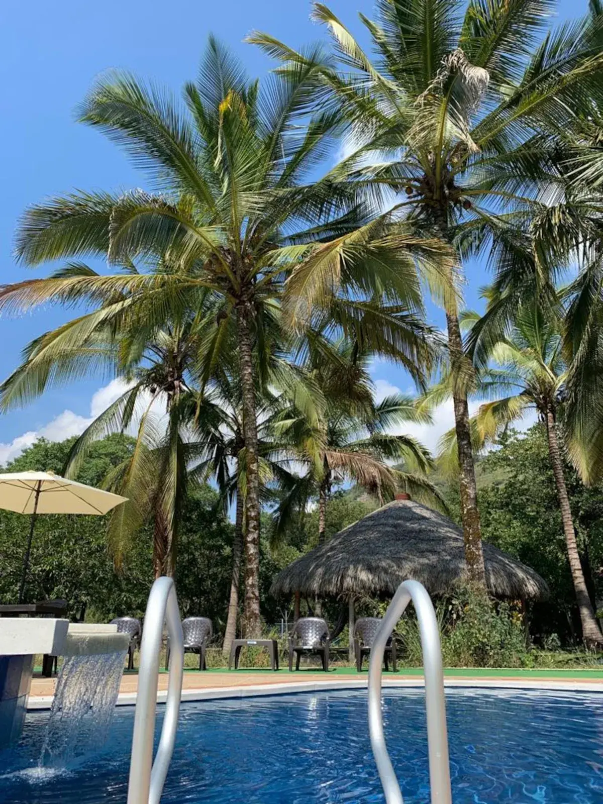 Piscina y kiosko entre palmas en La MariaCa, Útica